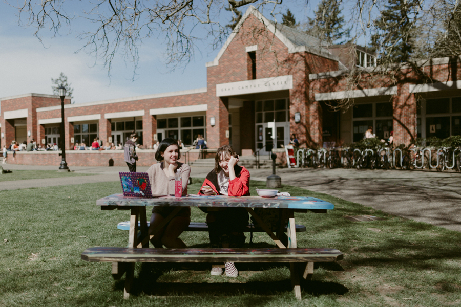 Two students sitting at a picnic bench on campus